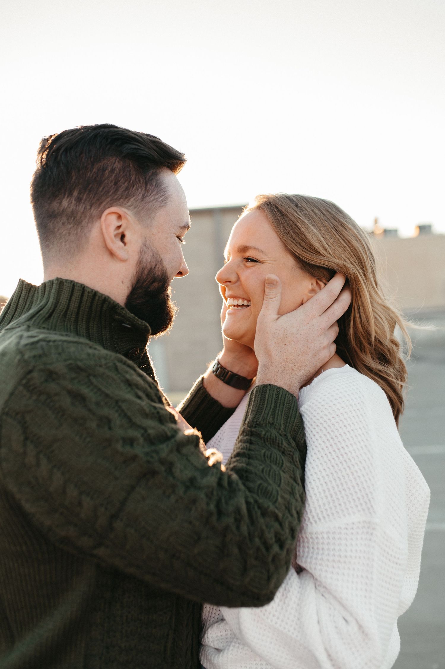 Tender moment between couple wearing knit sweaters during sunset portrait session.