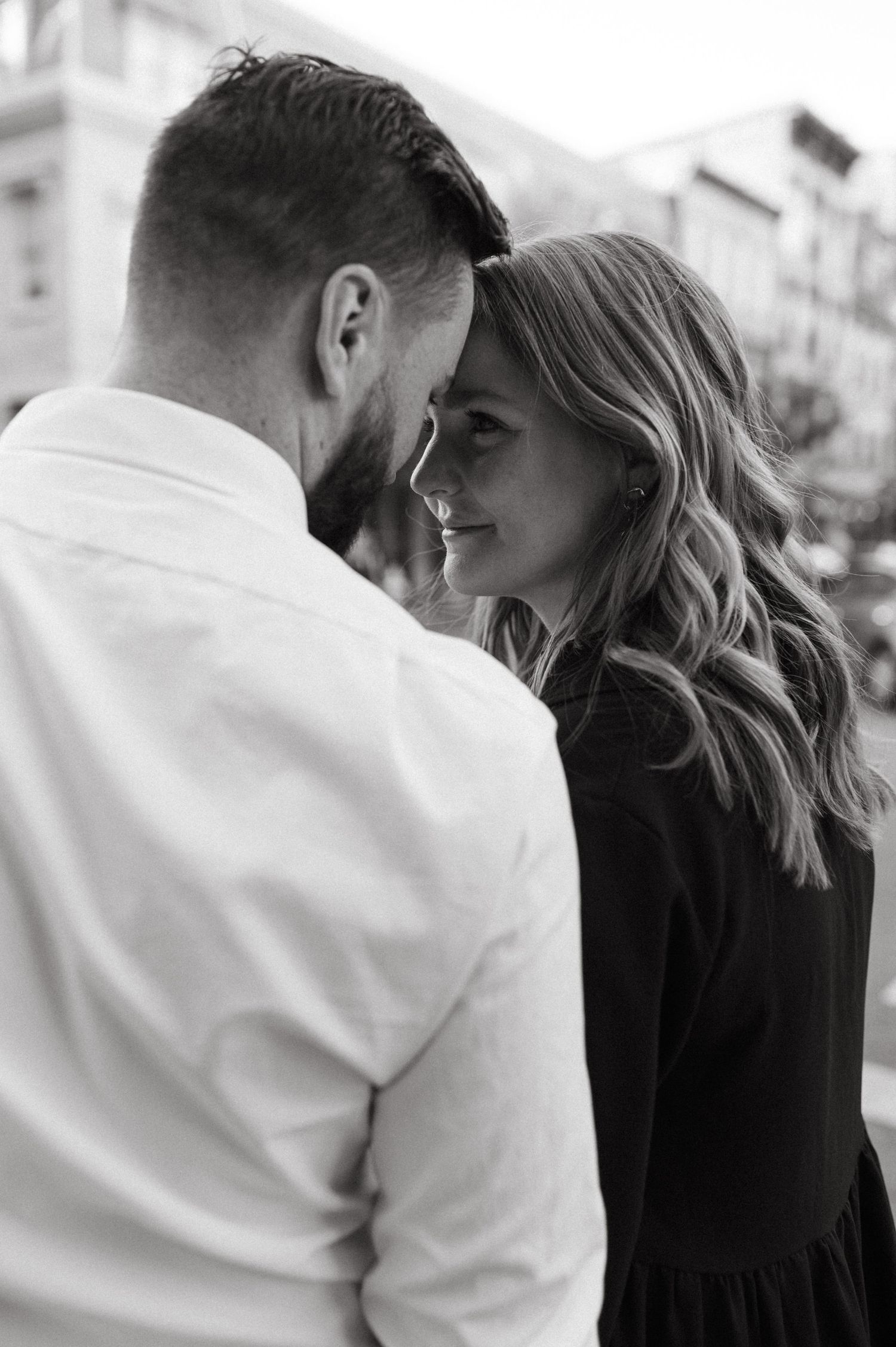 An intimate black and white portrait of a couple sharing a tender moment.