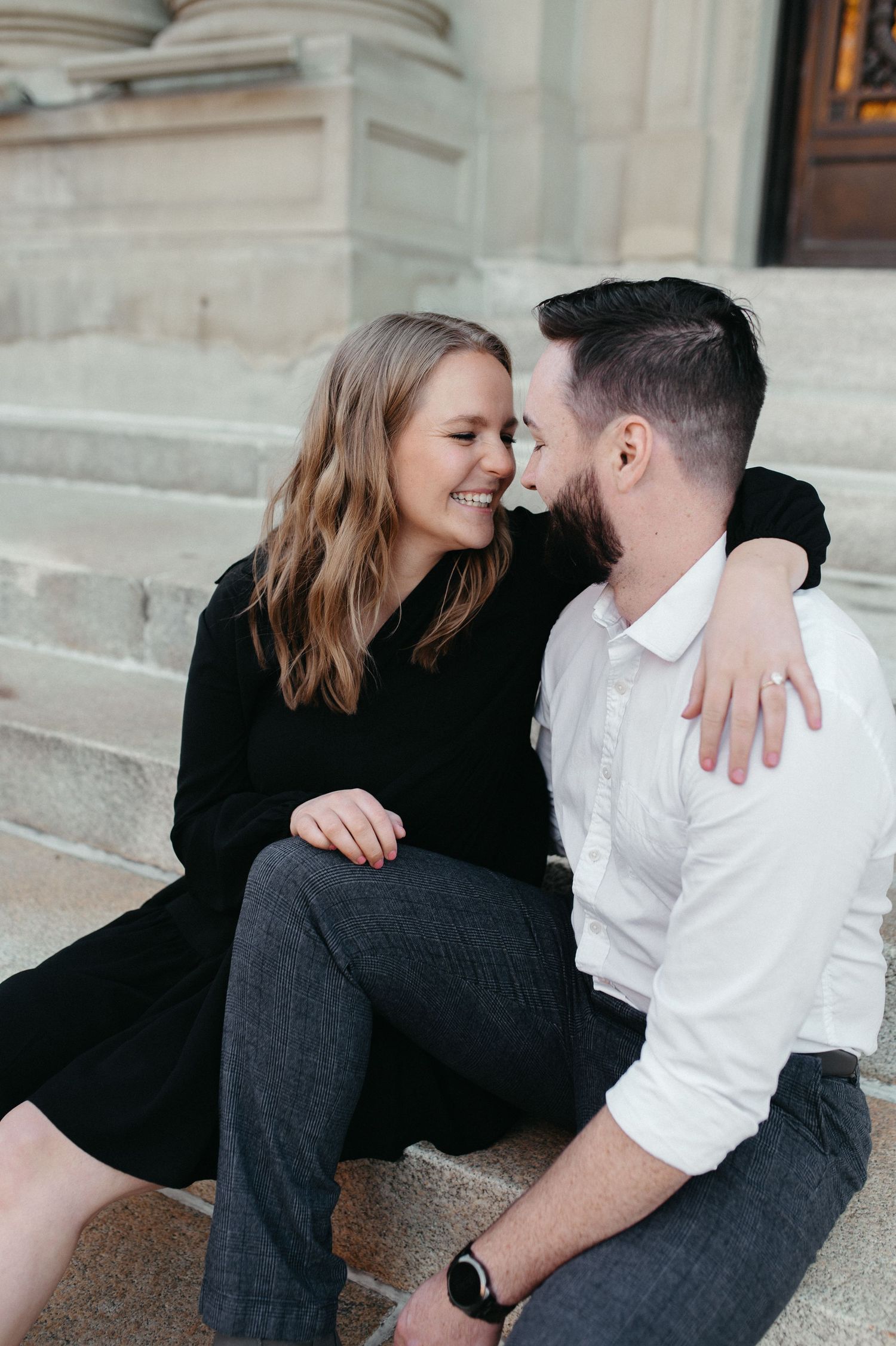 Couple laughing together while sitting on concrete steps of a historic building.