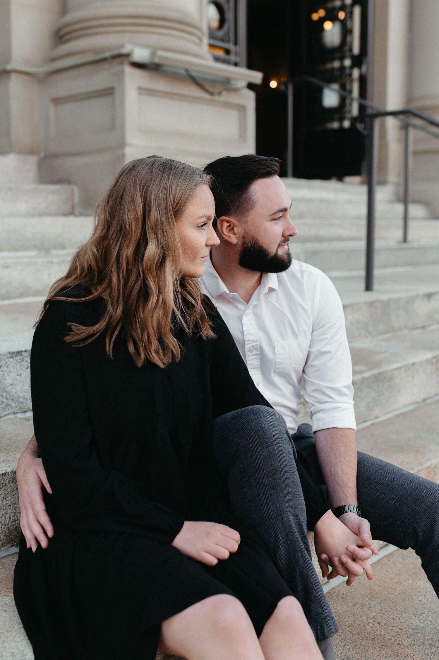 A candid moment captured of a couple sitting on stone steps during their engagement session.