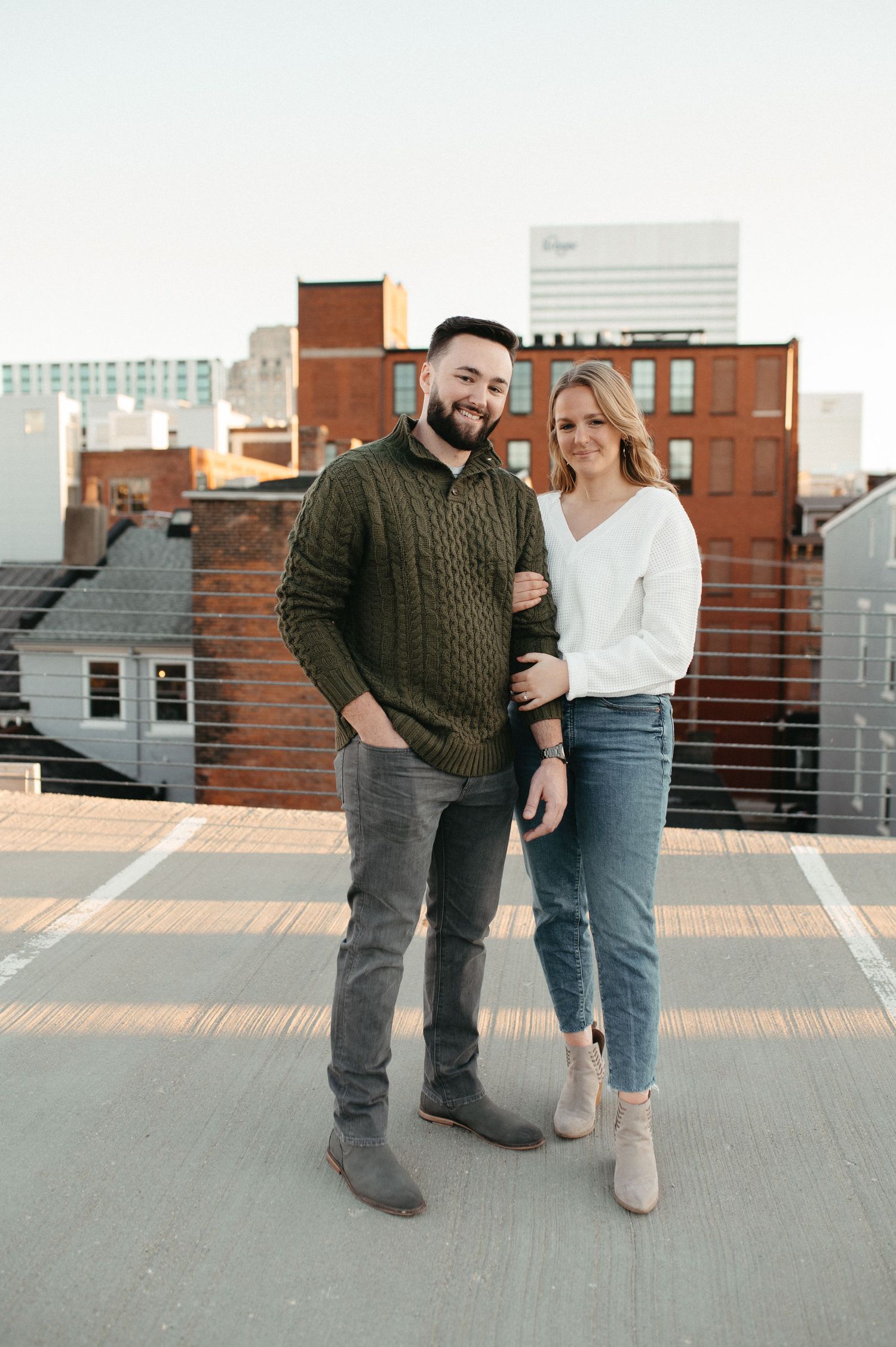 Couple in coordinated fall outfits standing together on an urban rooftop.