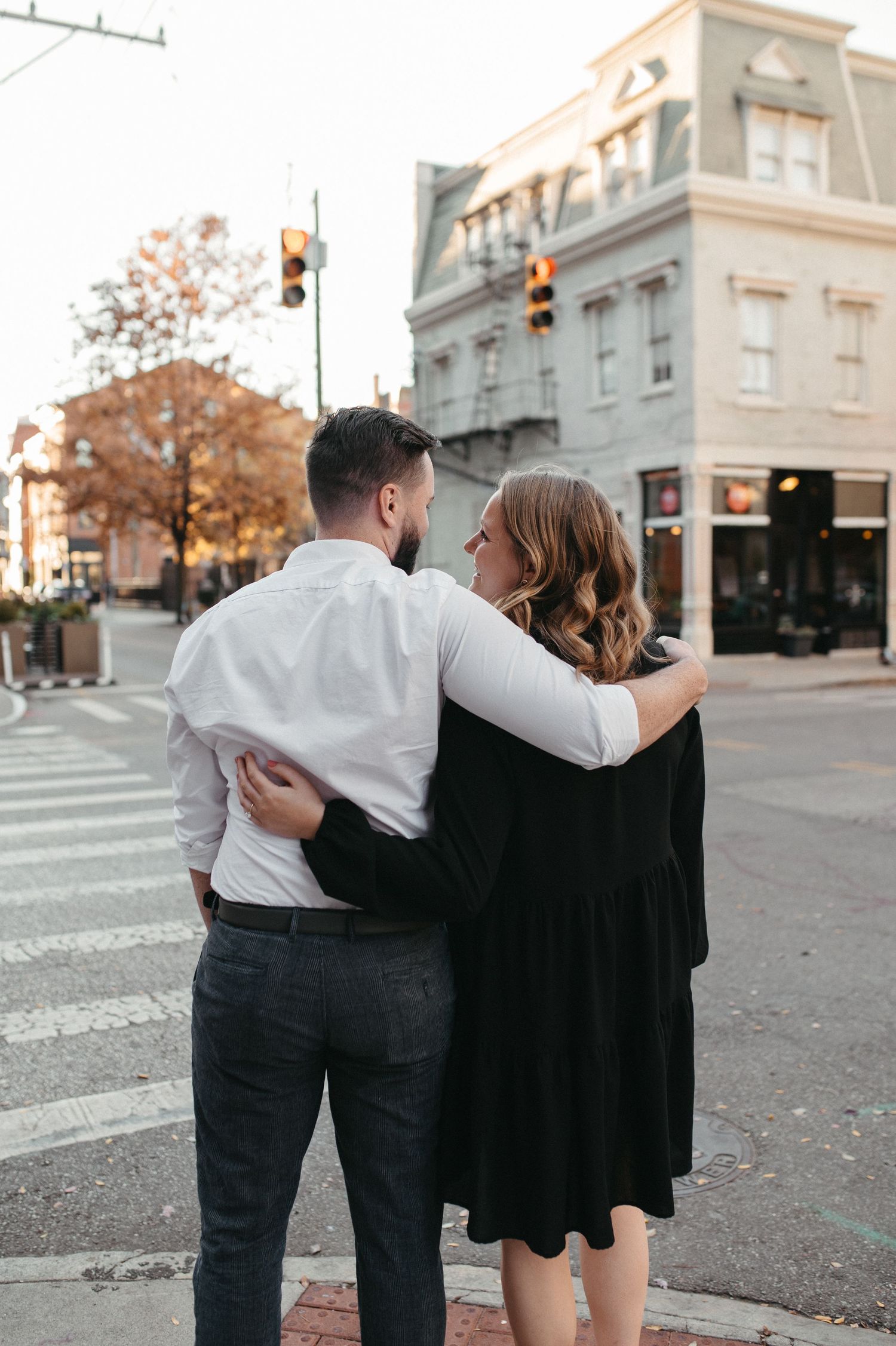 Couple sharing embrace on urban street corner during autumn.