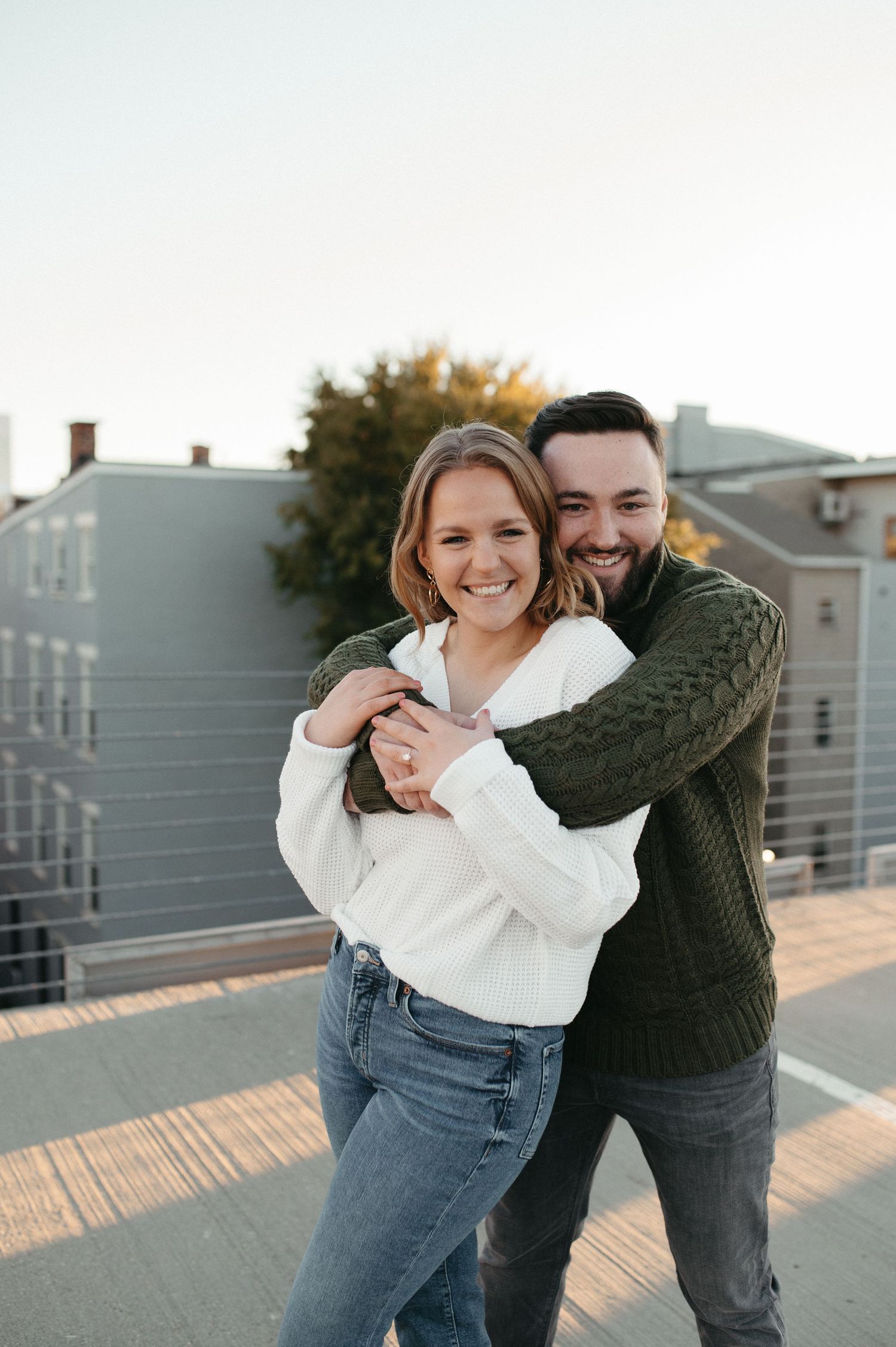 Couple laughing together in a warm embrace on a city rooftop.
