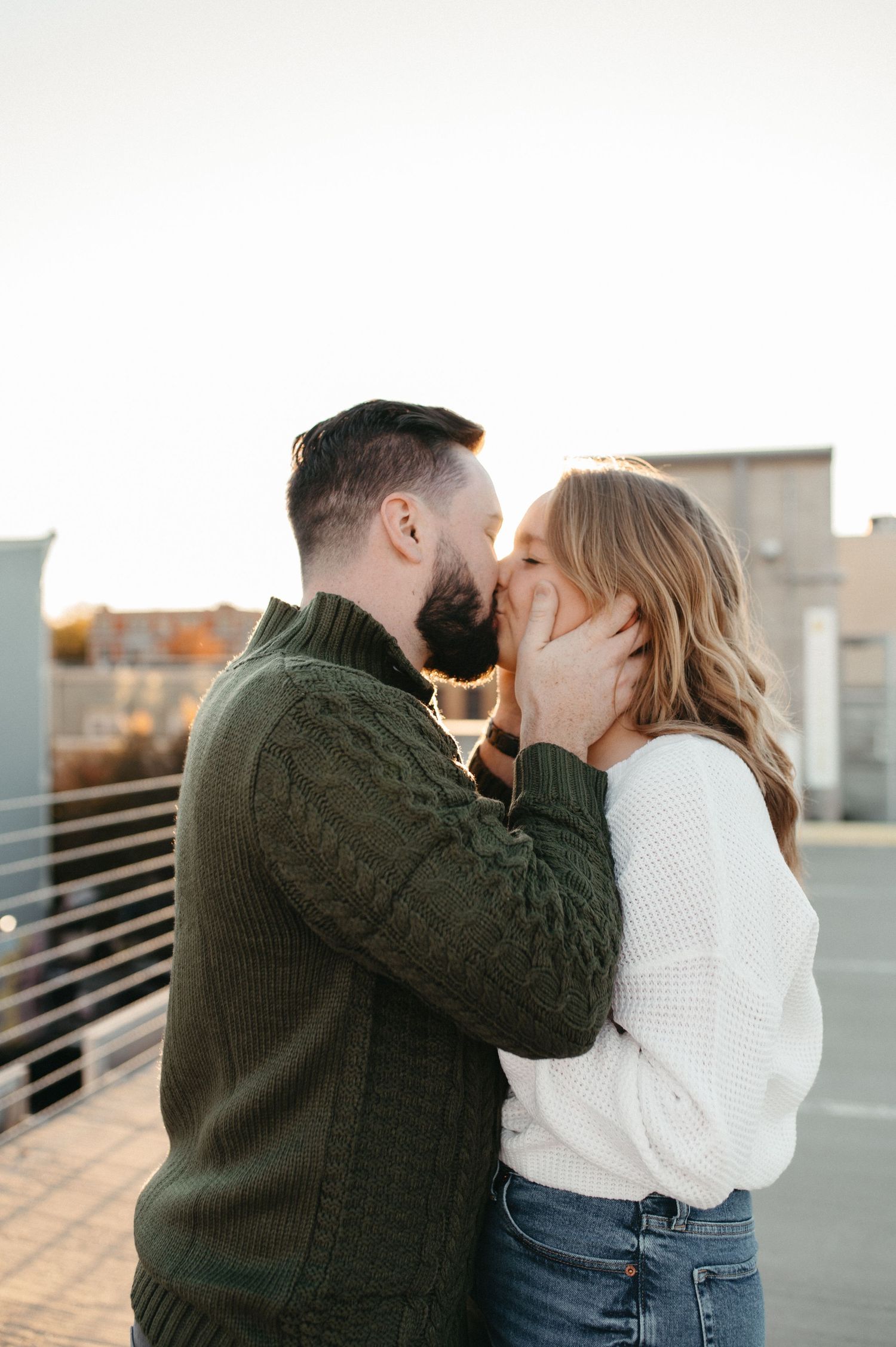 Intimate couple's portrait with dark green and white sweaters during golden hour.