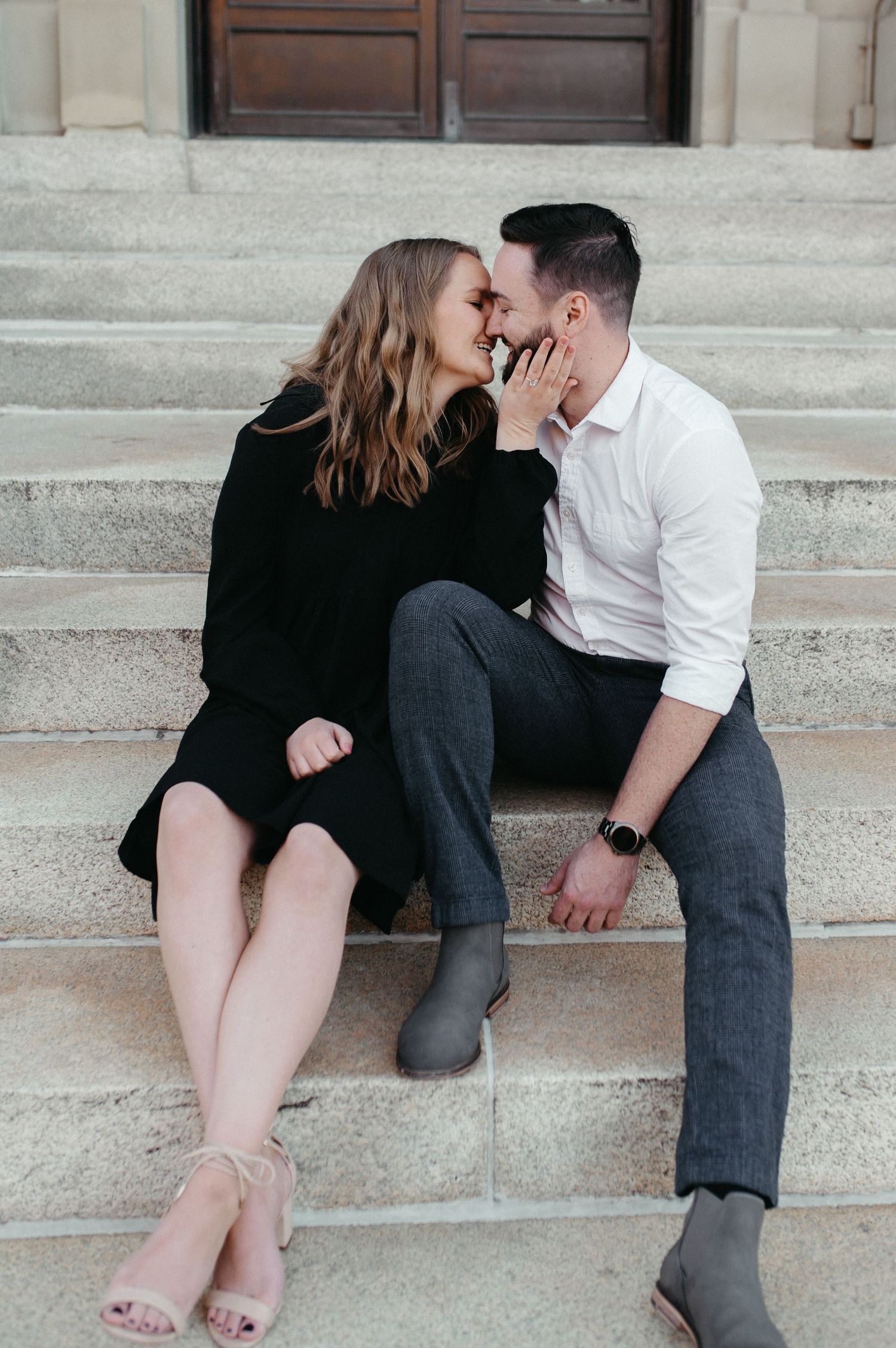An intimate moment shared between a couple sitting on stone steps during their photoshoot.