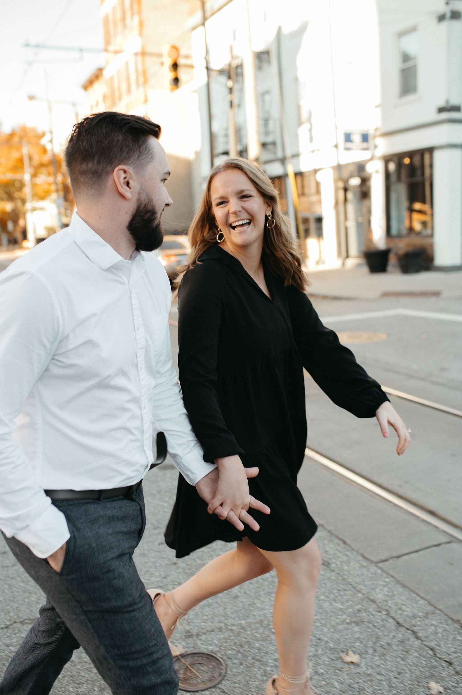Happy couple laughing while walking down an urban street during golden hour.