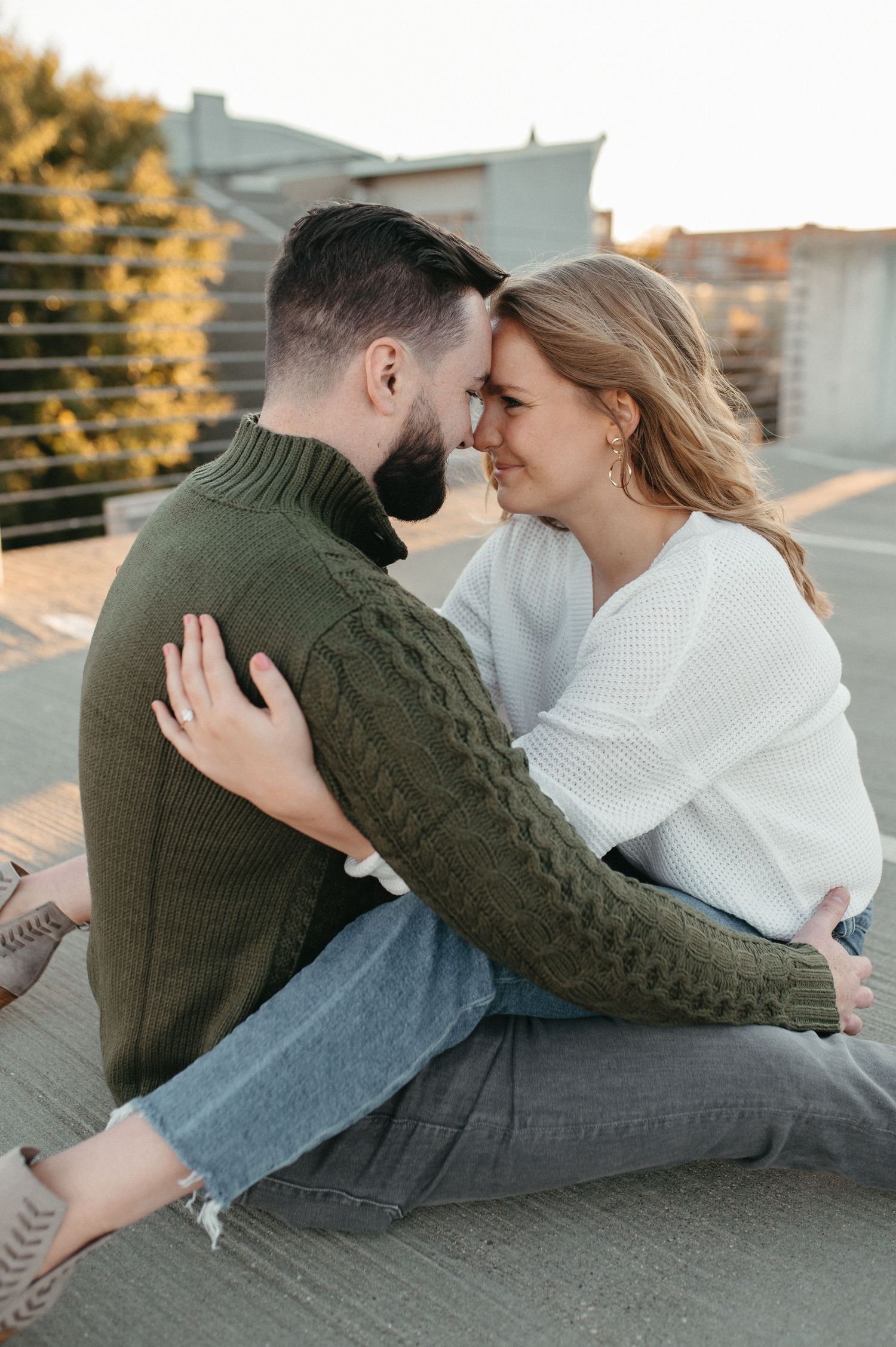 An intimate moment between a couple in winter sweaters during their rooftop photo session.