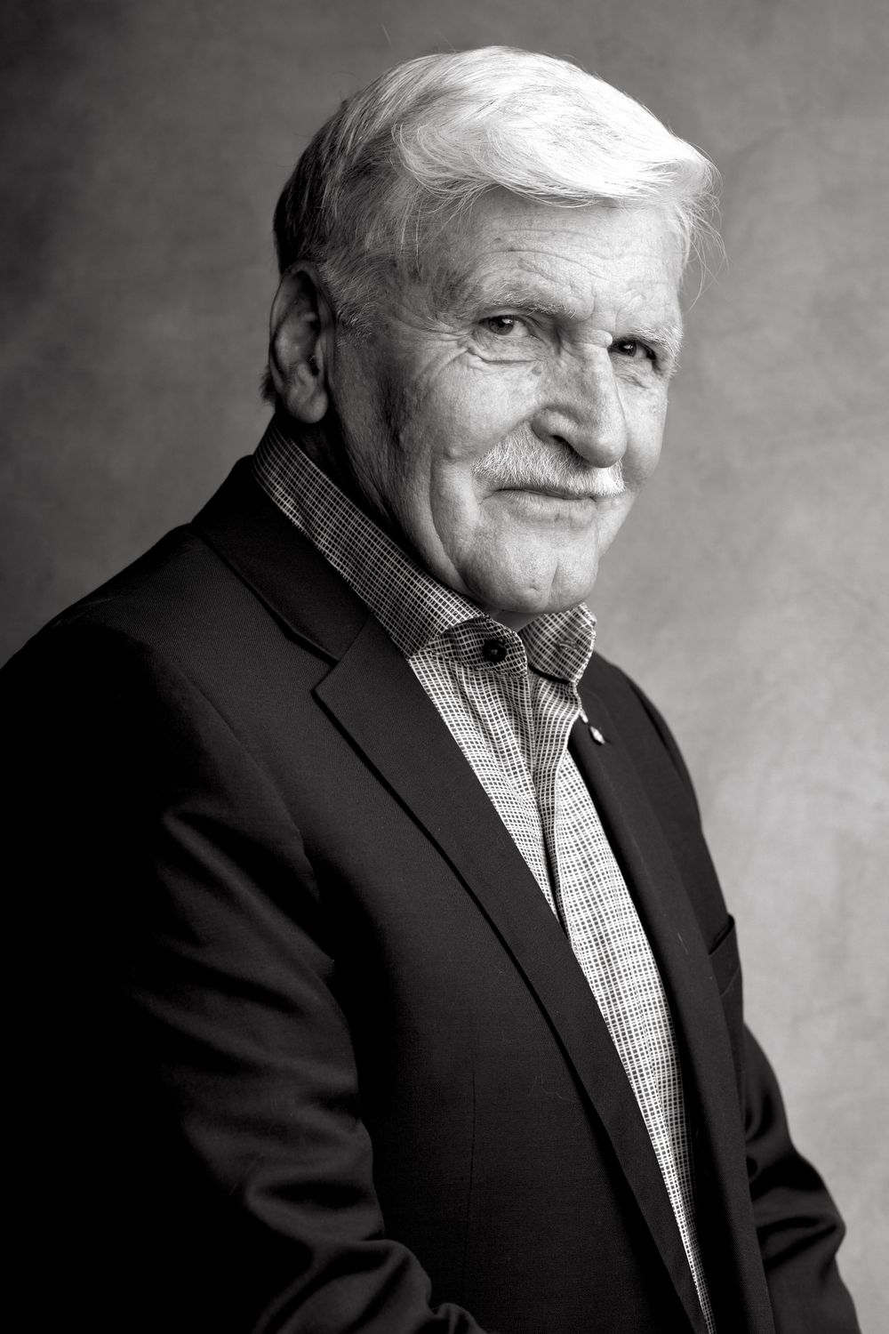 Professional black and white portrait of a senior man in business attire smiling at the camera.