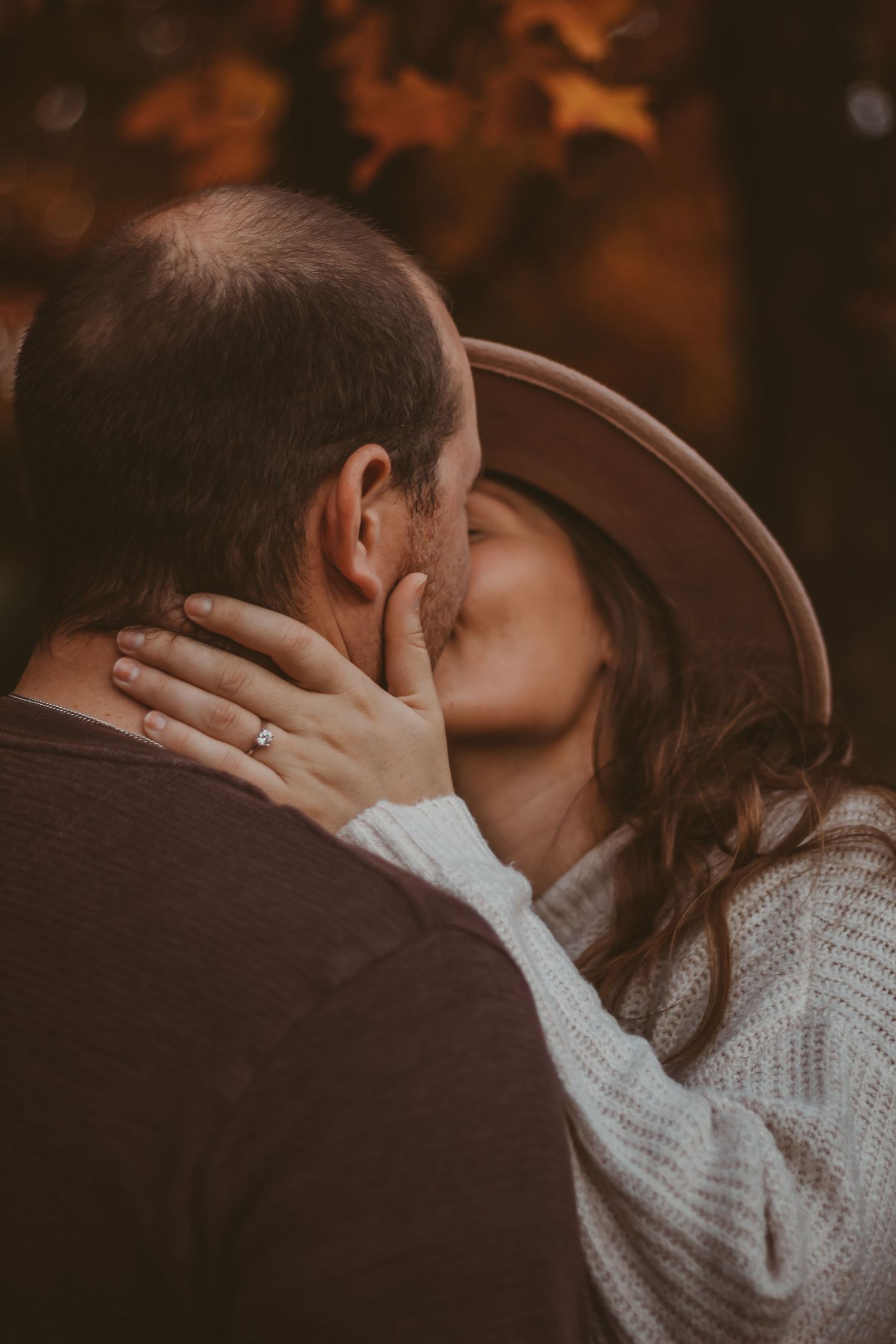 A romantic couple sharing an intimate kiss outdoors during golden hour.