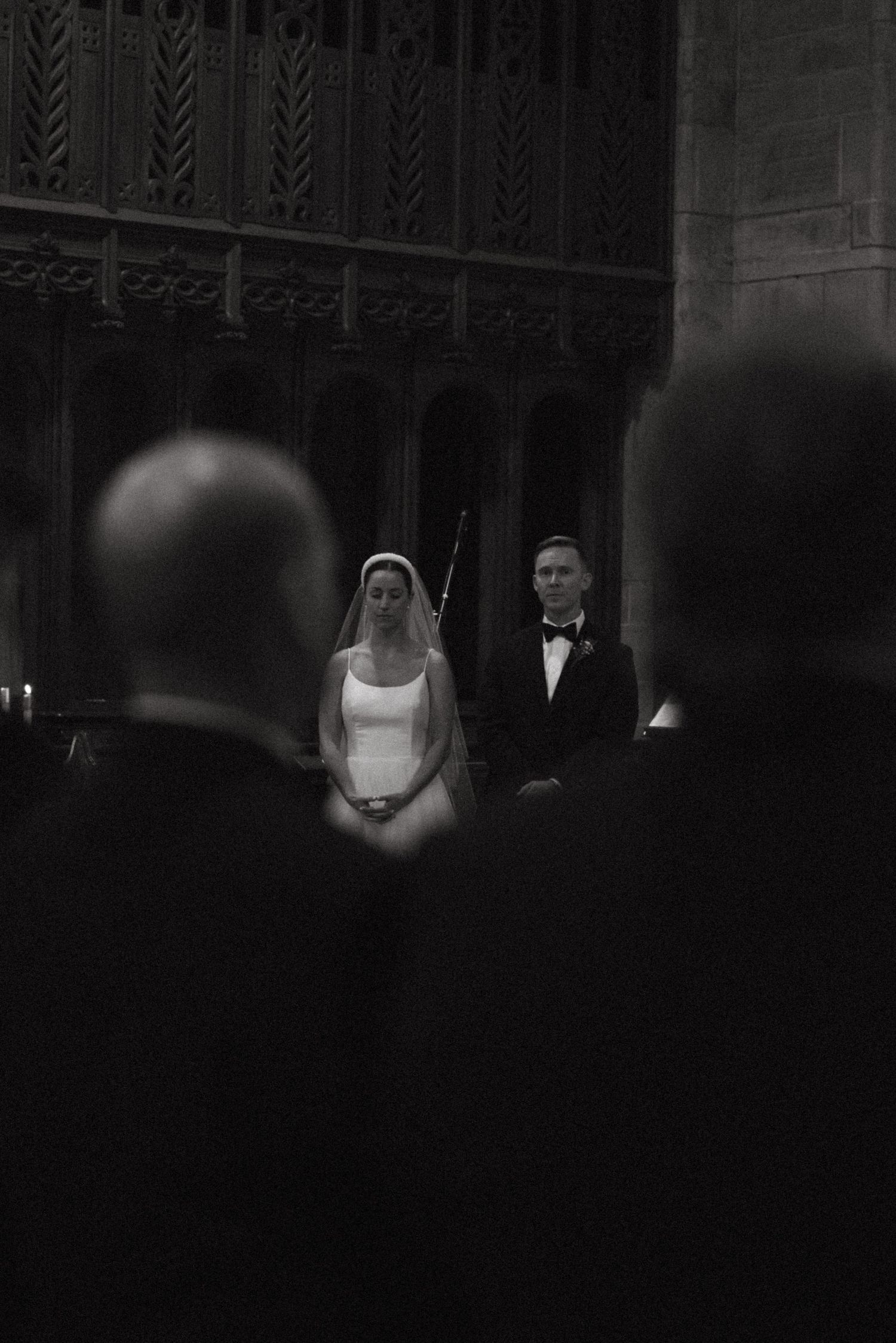 Black and white ceremony photo in a dramatic church setting with architectural details.
