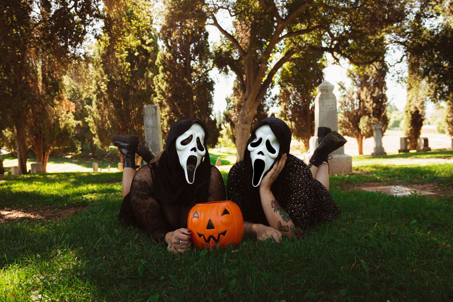 Halloween scene with Scream masks and pumpkin decorations arranged outdoors.