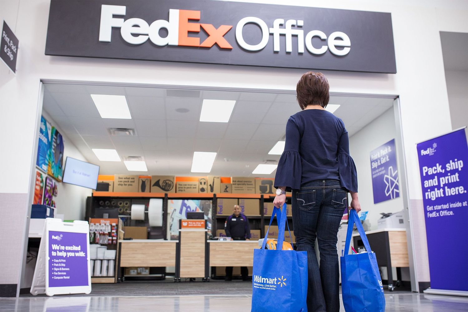 A Walmart customer walks into an in-store FedEx Office Store to ship her purchases.