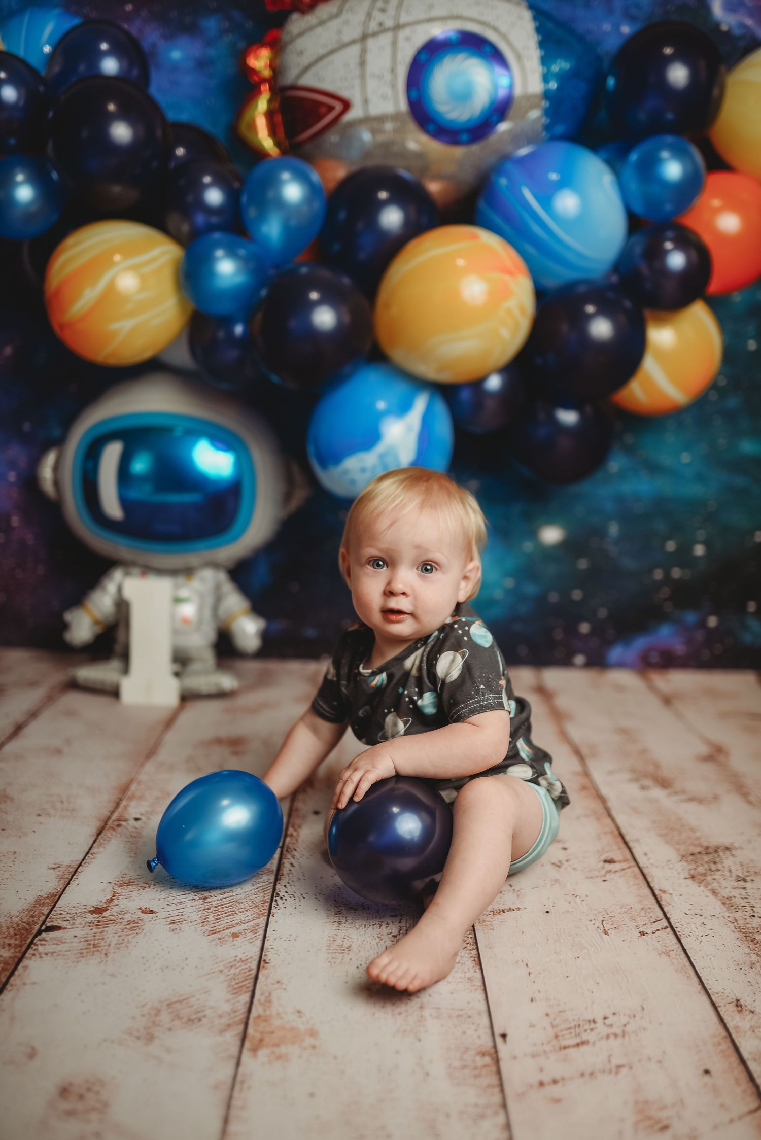 Space themed photo setup with colorful balloons and planetary decorations.