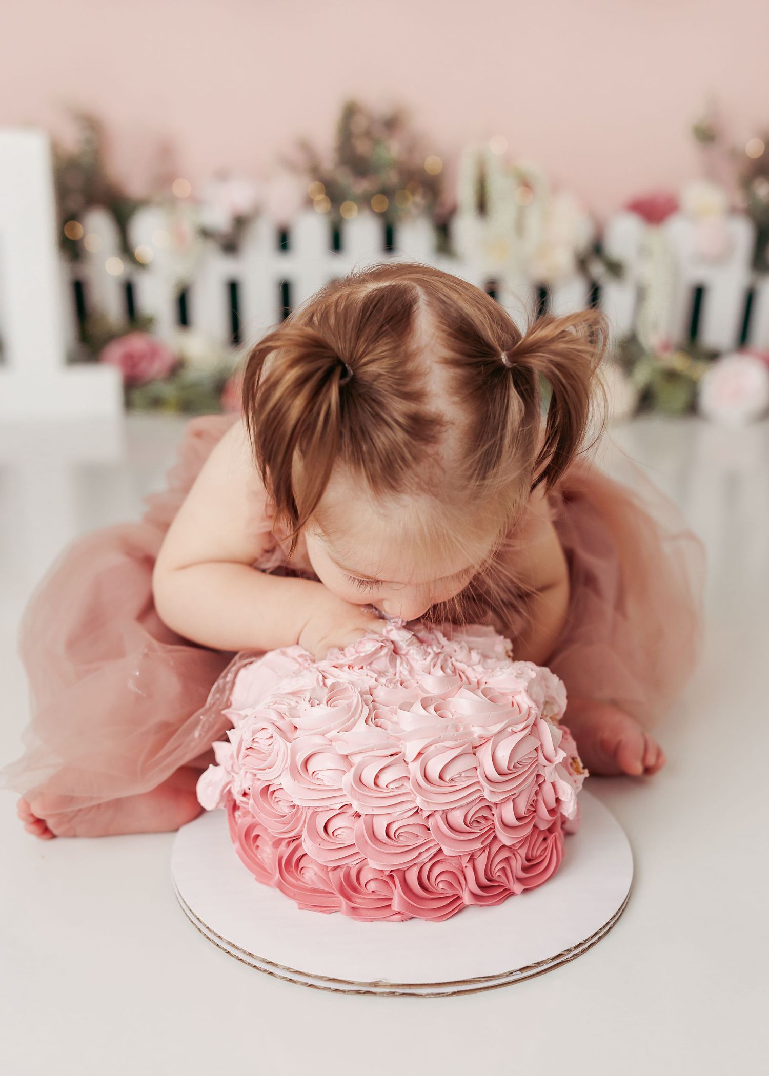 baby girl eating cake at her cake smash in Tulsa
