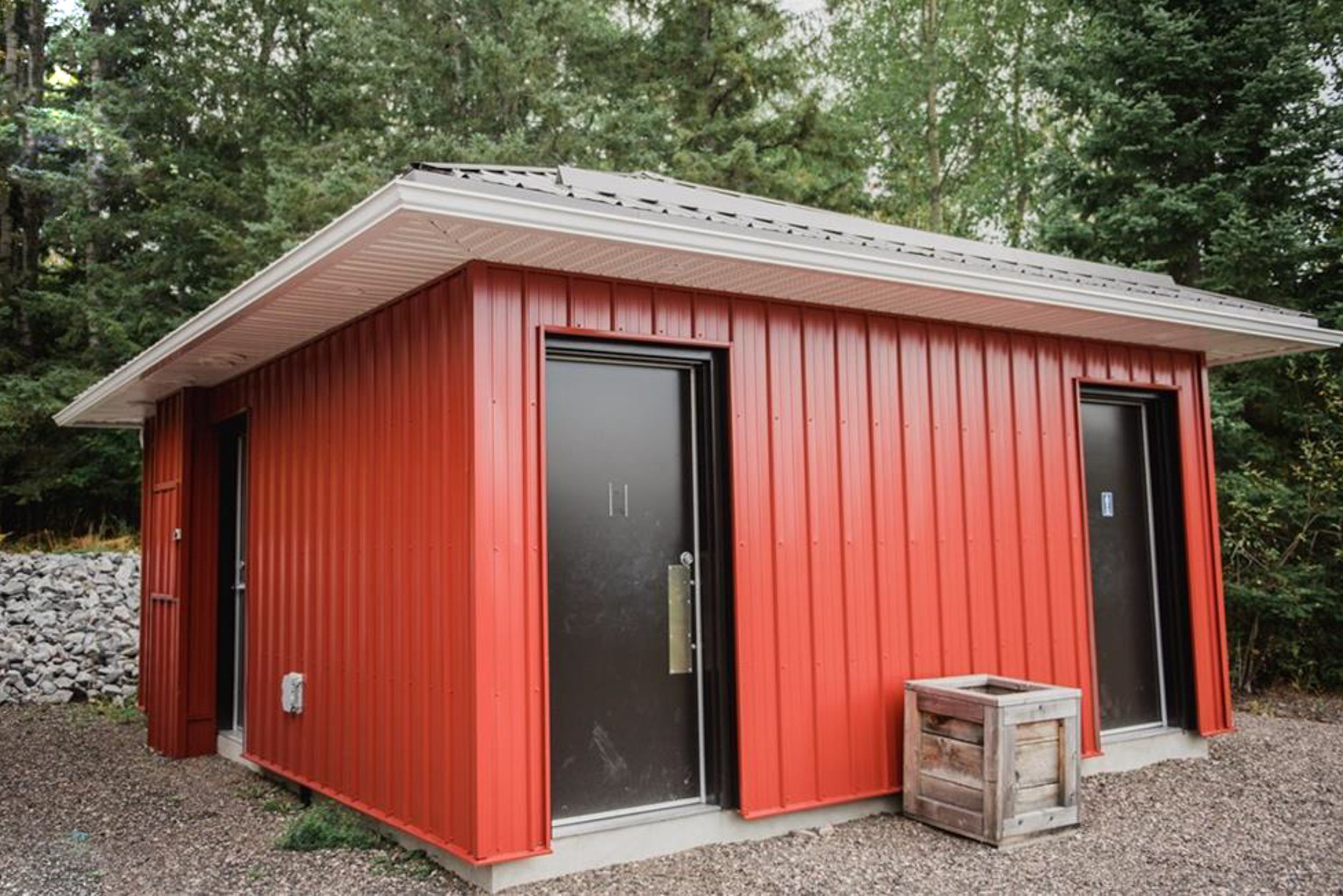Small red modern outbuilding with black doors and wooden crate decorations.