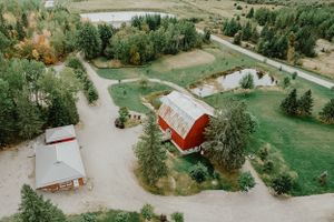 Aerial view of a rustic red barn wedding venue surrounded by green landscaping and trees.