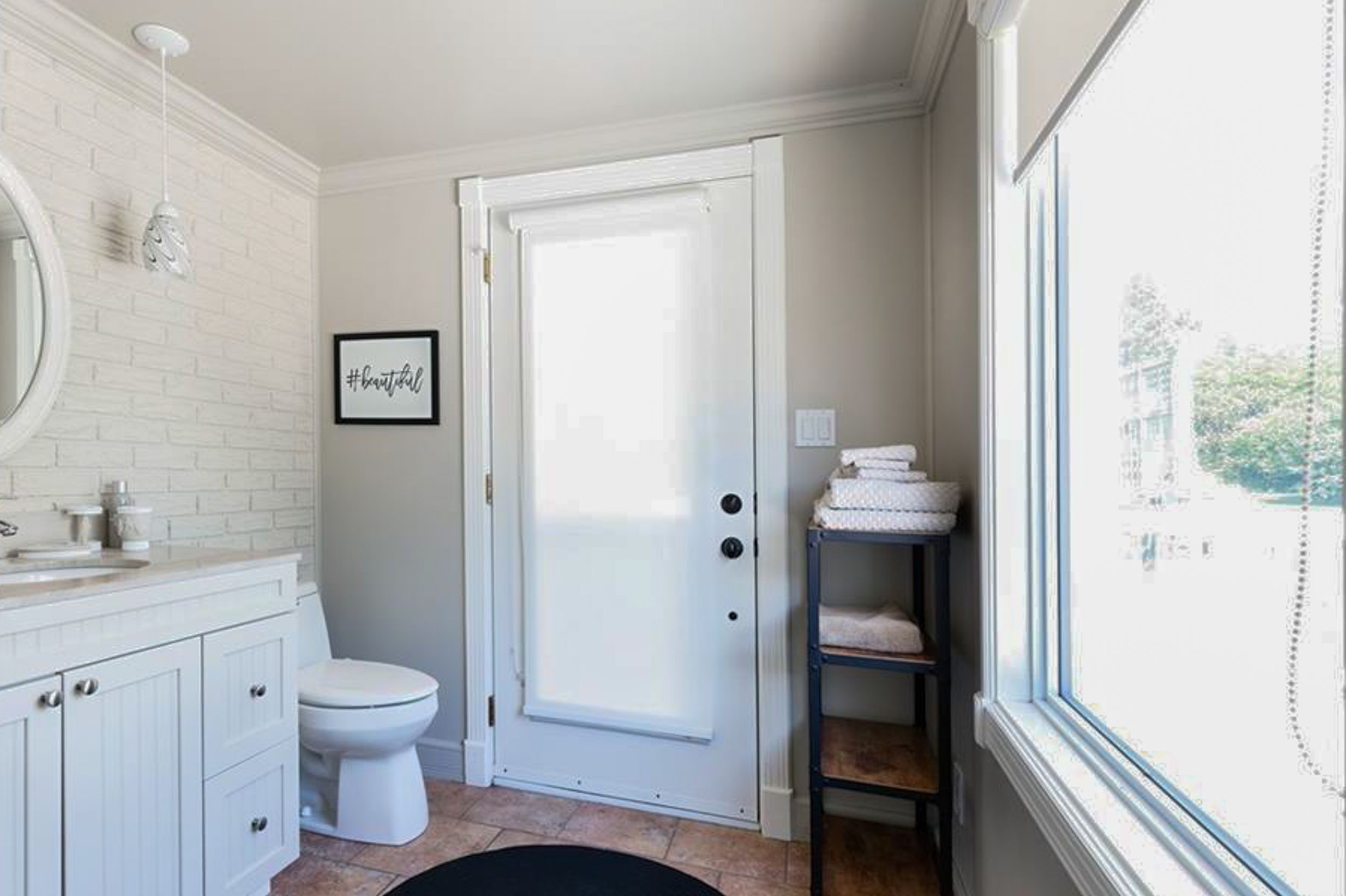 Bright bathroom interior with white vanity, frosted door, and built-in shelving unit.