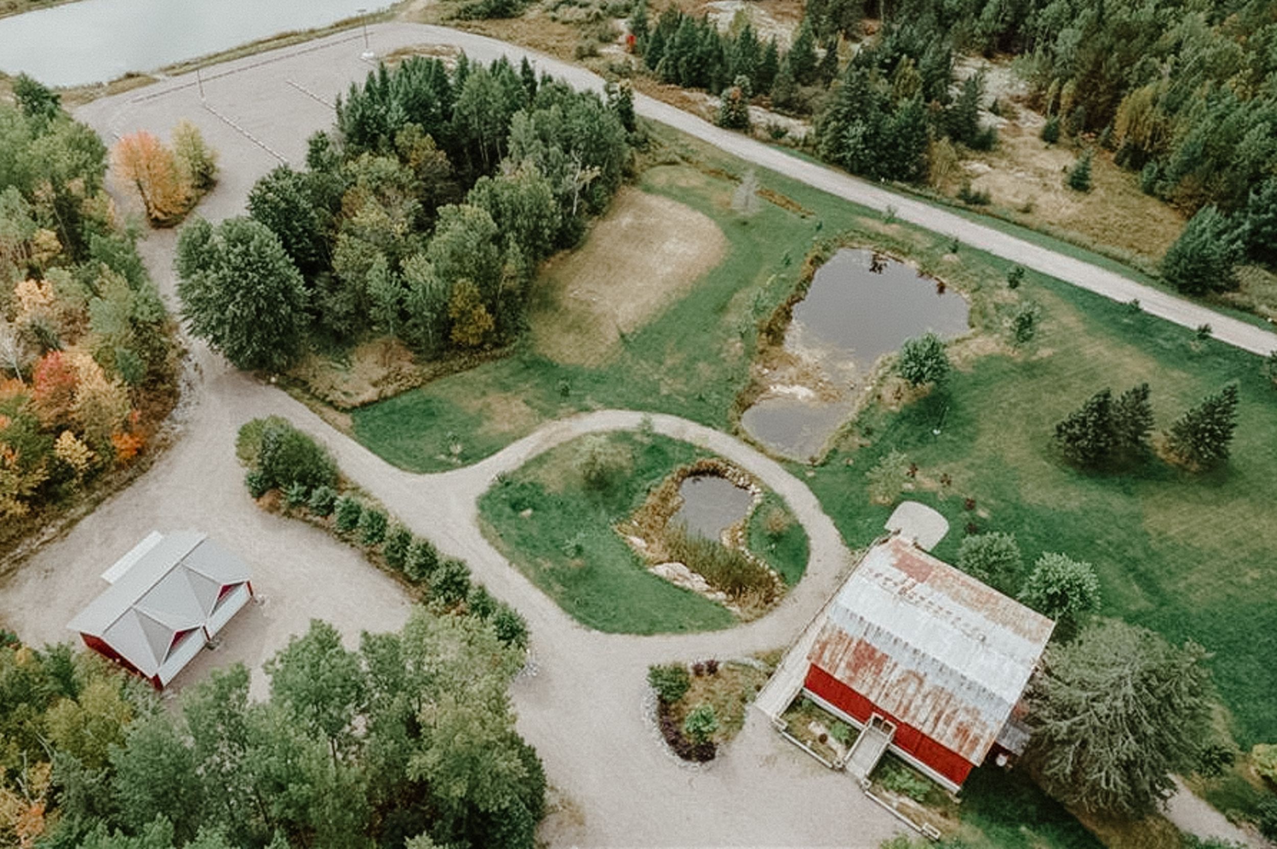 Bird's eye view of a circular garden path leading to a red barn venue with surrounding grounds.