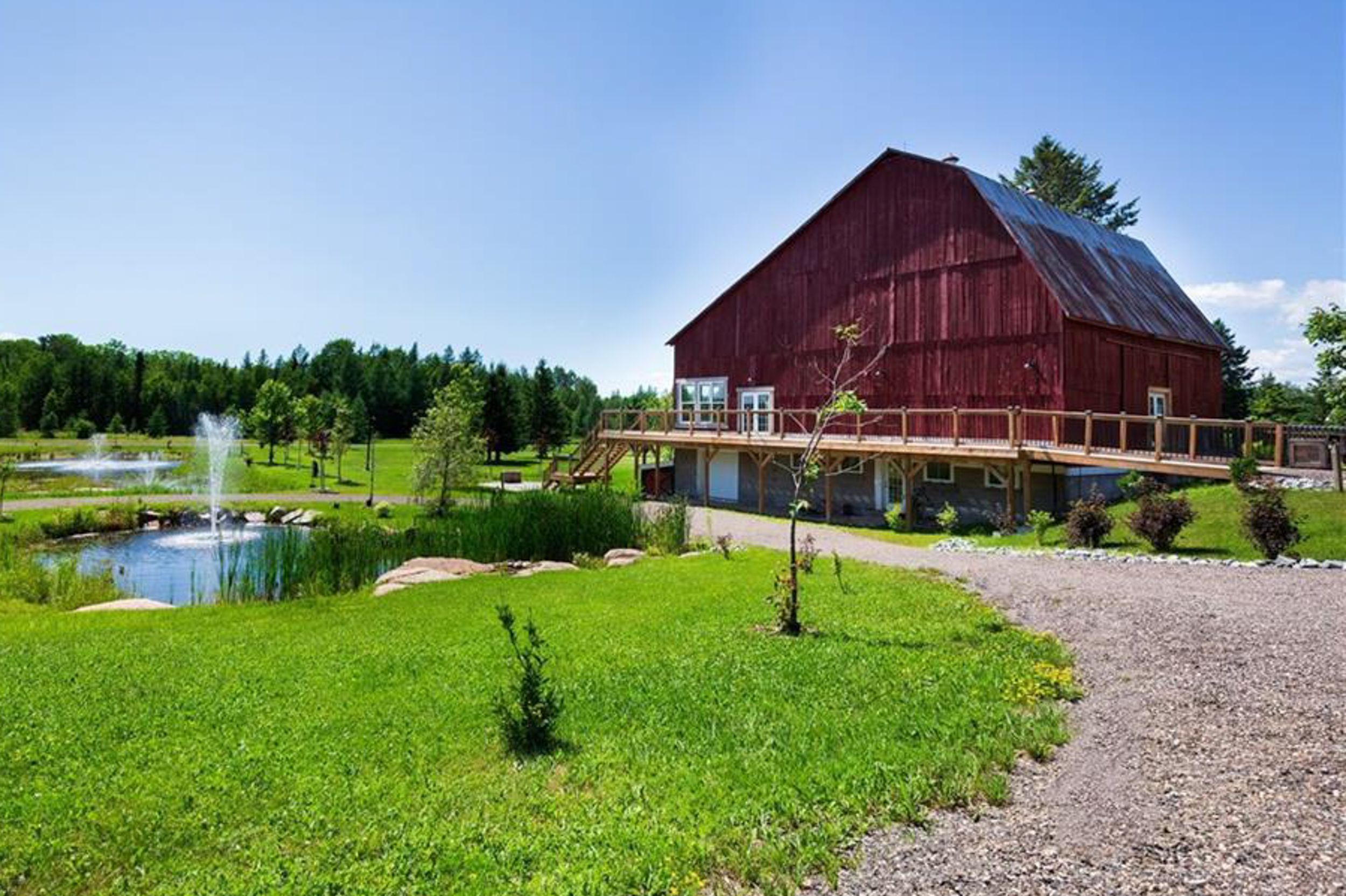 Large red barn next to a decorative pond with fountain and landscaped grounds.