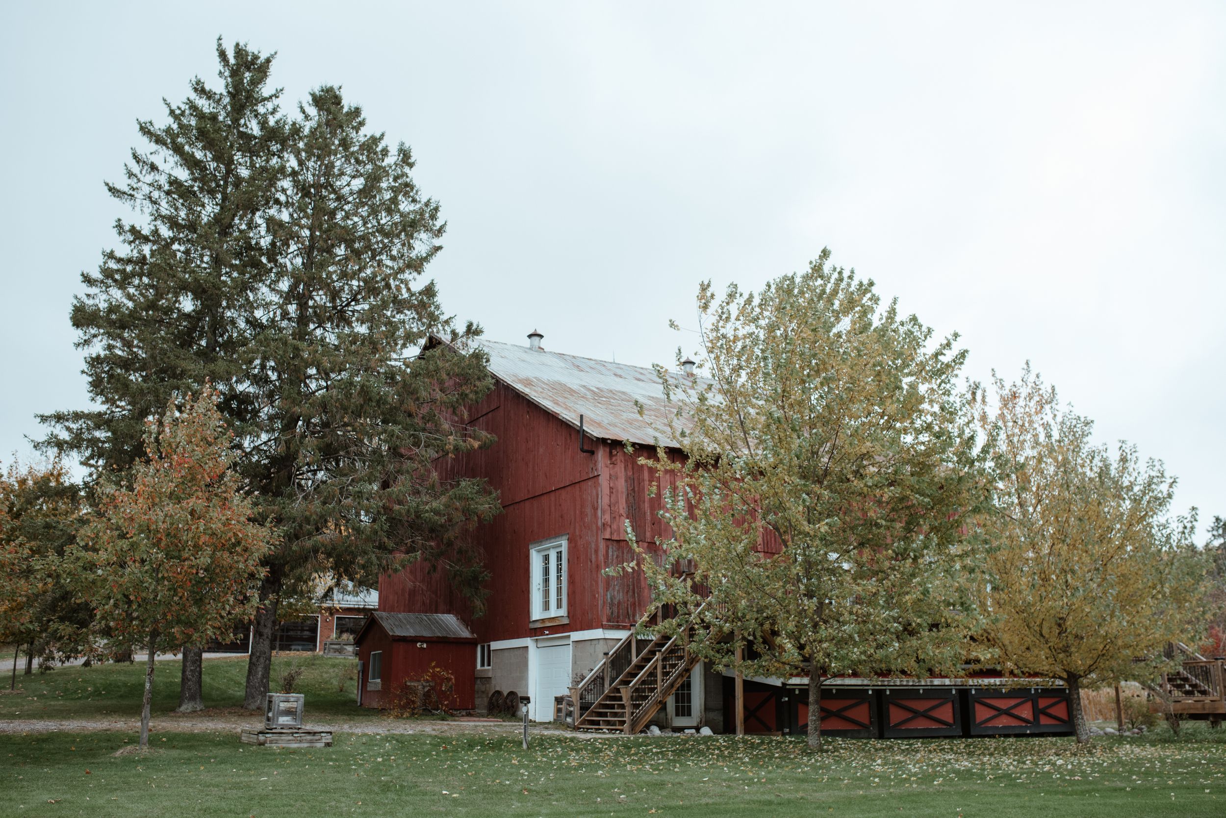 Classic red barn with wooden deck surrounded by autumn trees.