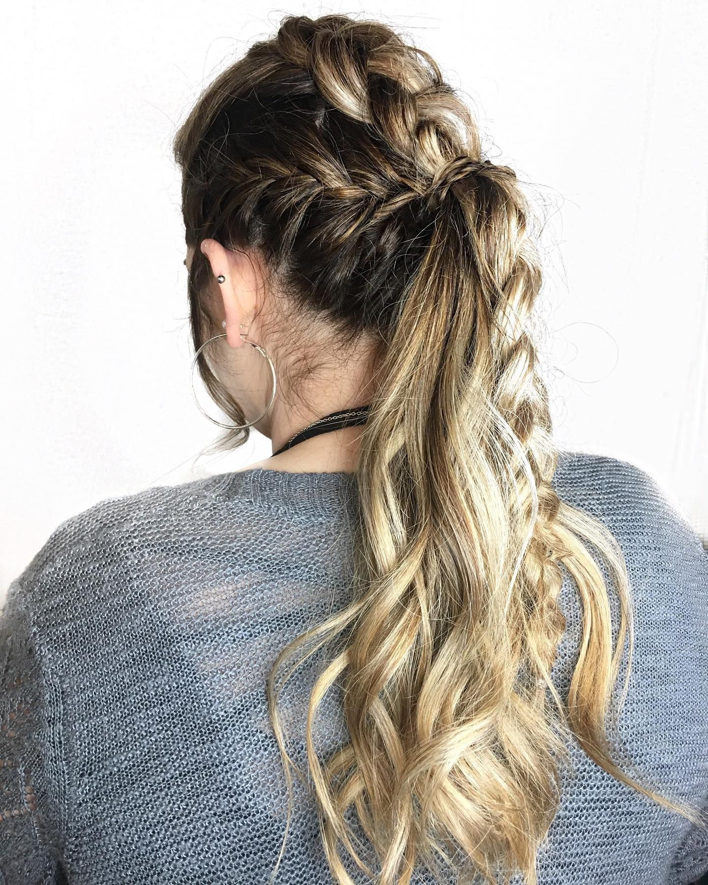 Intricate french braid hairstyle flowing into long wavy blonde hair shown from behind.