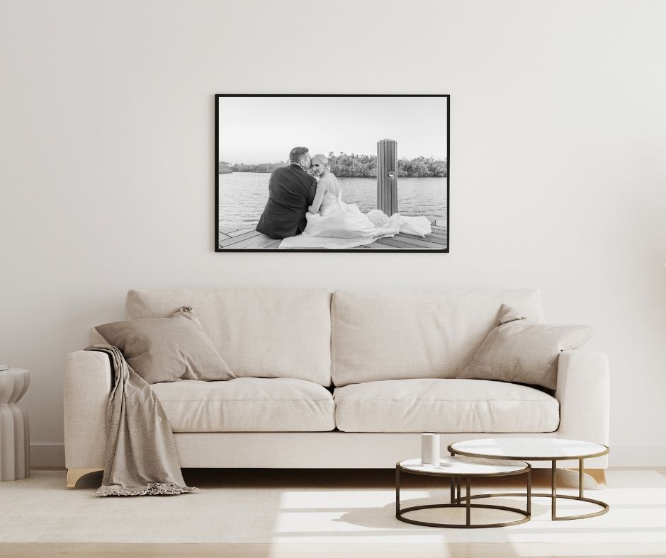 Black and white photograph of a beach scene displayed above a beige couch in a modern living room.