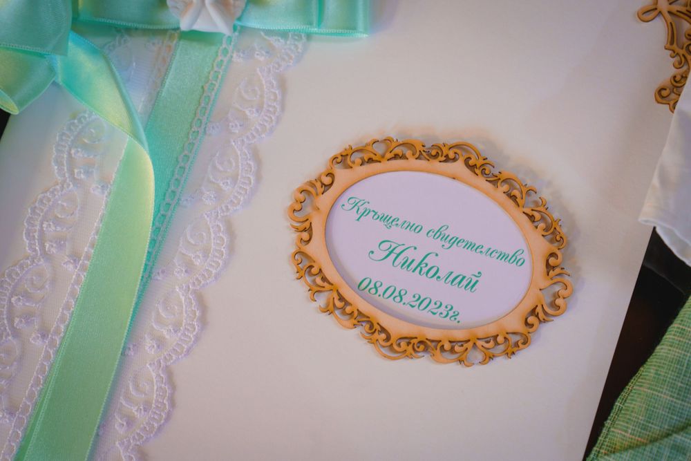 Decorative frame with mint green ribbon on a white background showing baptismal event details.