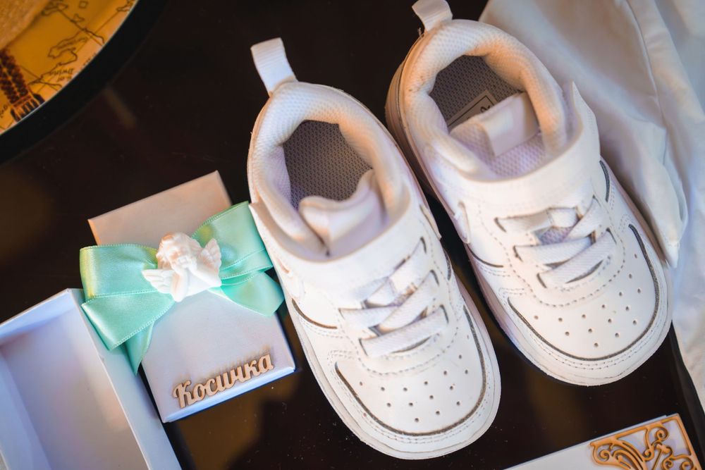 White baby shoes and mint green bow accessories arranged for a baptism ceremony.