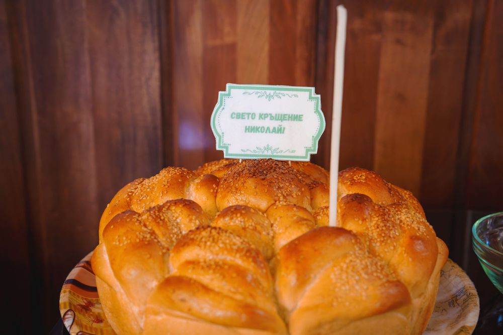Traditional ceremonial bread with a small decorative sign on top sits on display at a religious event.