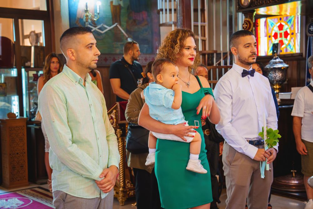 Christening ceremony in progress with attendees standing near the altar in formal attire.