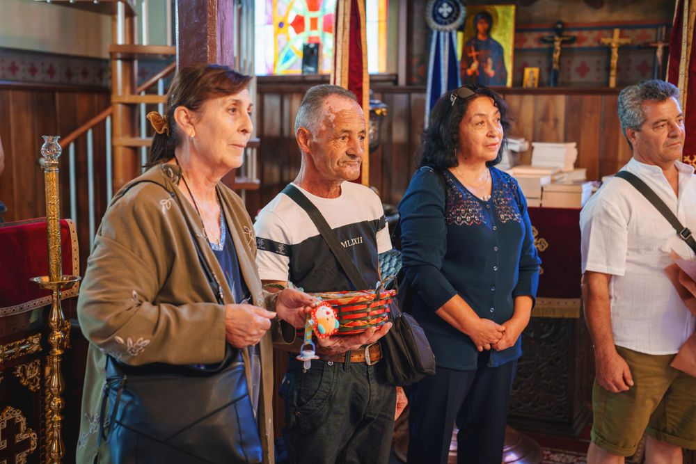 Church attendees watching a religious ceremony in a traditional wooden-paneled sanctuary.