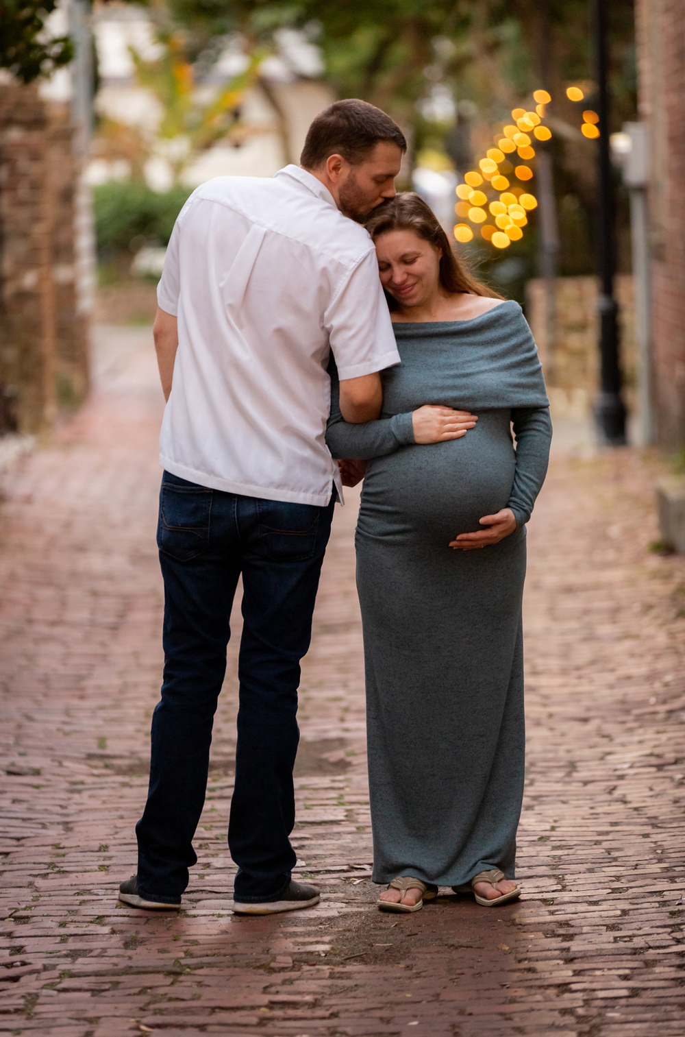 Dad kisses pregnant mom on cobblestone street