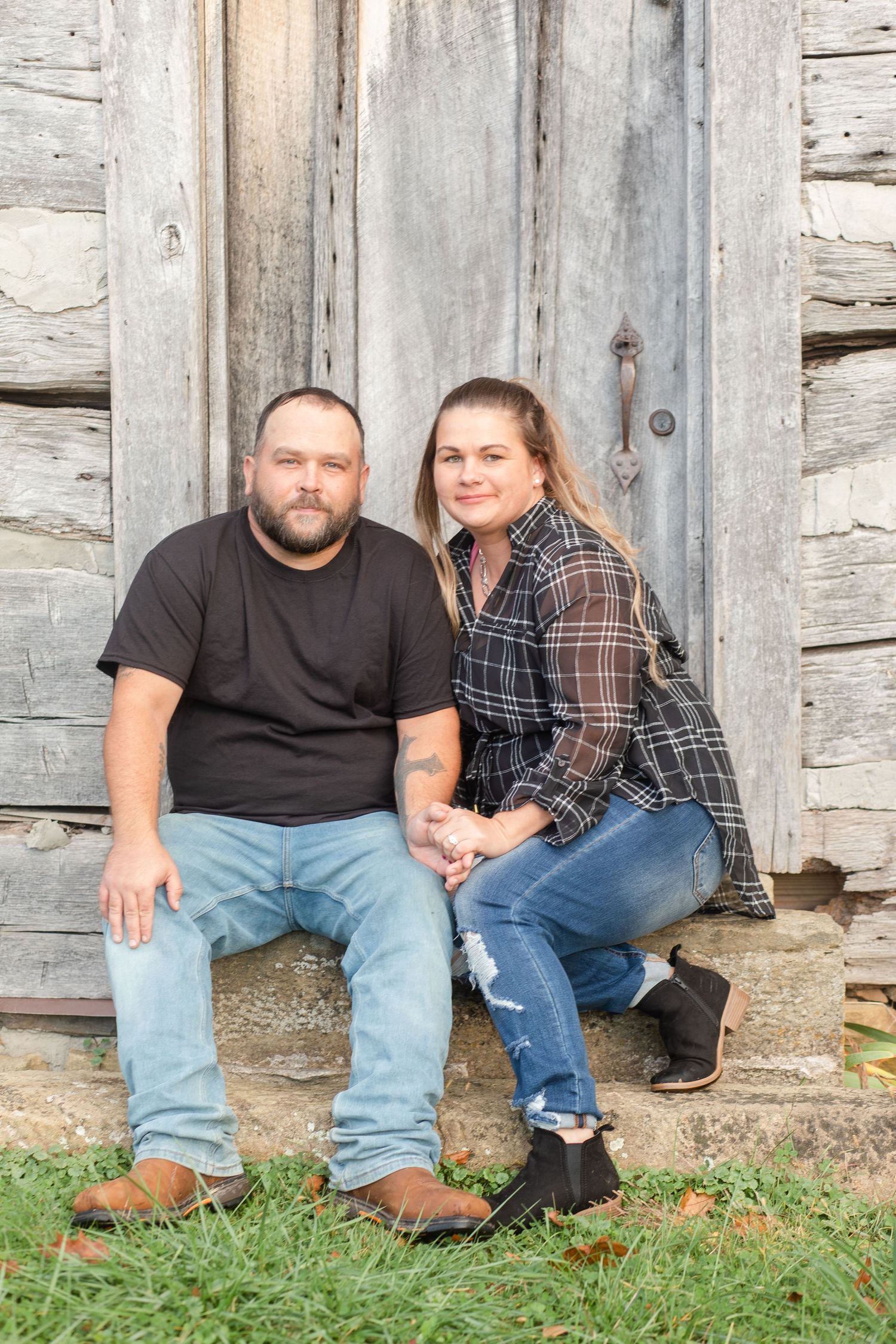 Casual portrait session against a rustic log cabin wall with fall leaves on the ground.