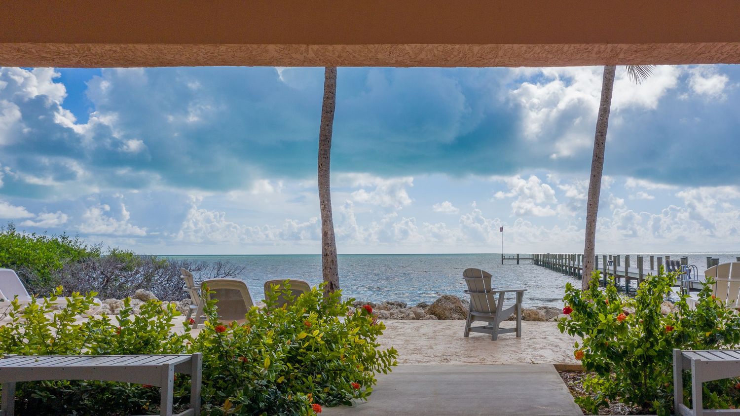 Ocean view through multiple windows showing palm trees and blue sky.