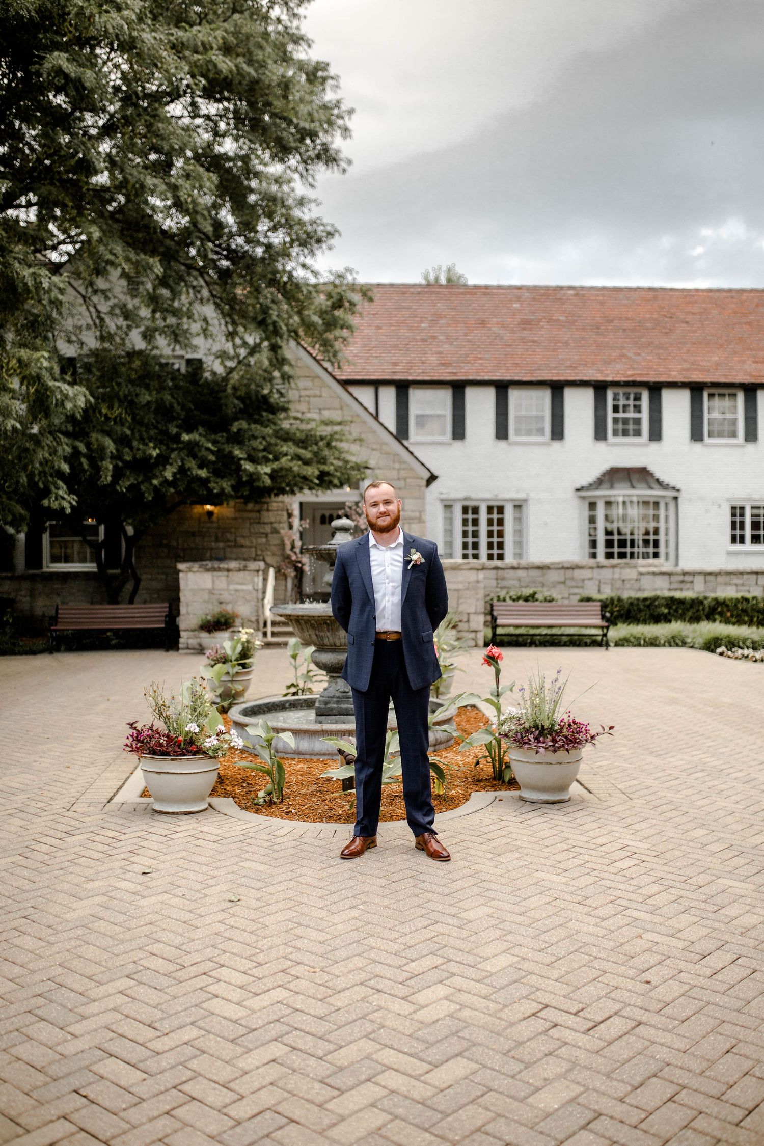 A formal wedding portrait in front of a classic white colonial style building with landscaping.