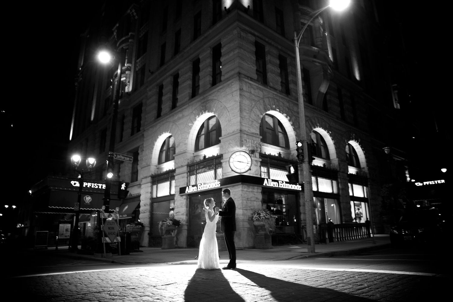 A dramatic black and white cityscape photo featuring a silhouetted couple against illuminated architecture.