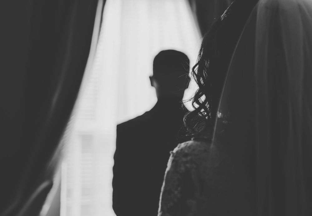 Silhouettes show wedding preparation moments in a brightly lit room.