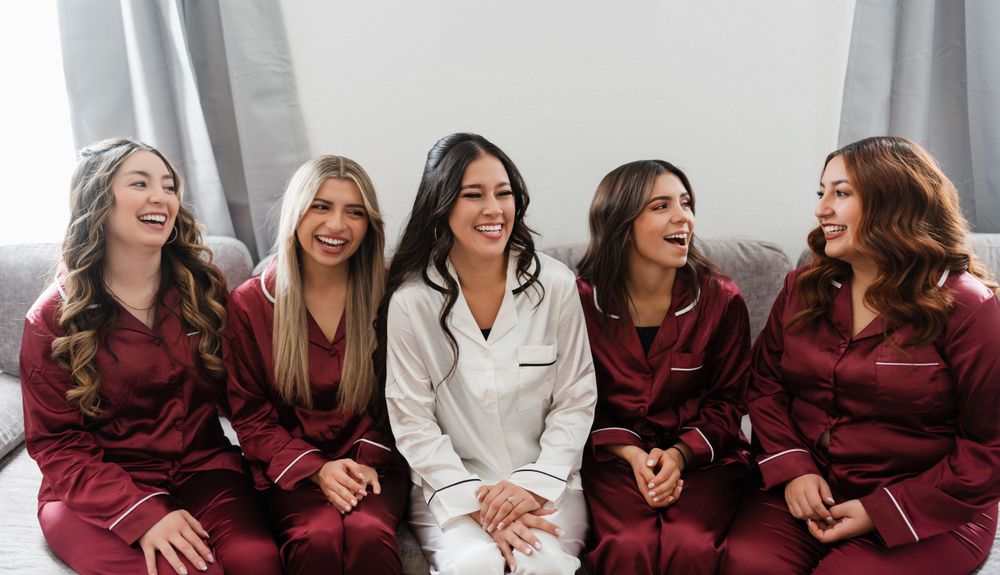 Bridesmaids in burgundy robes share joyful moments during wedding preparations.