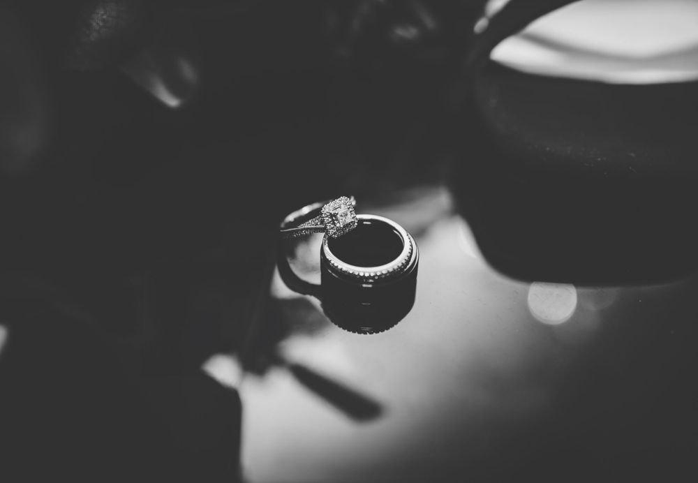 Wedding rings photographed in dramatic black and white lighting.