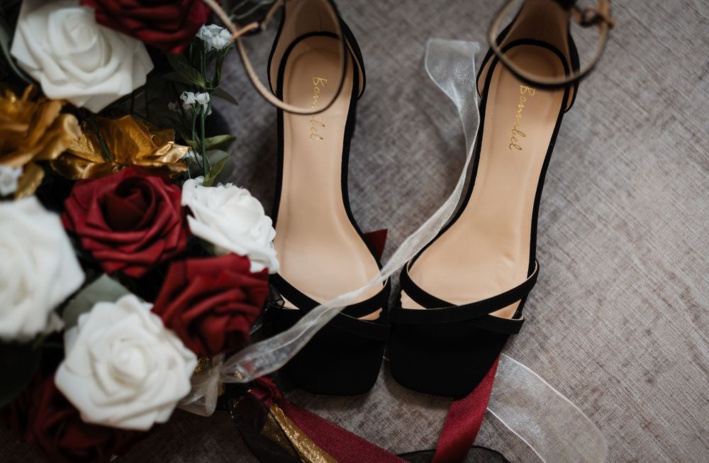 Wedding accessories including red and white roses with black formal shoes.