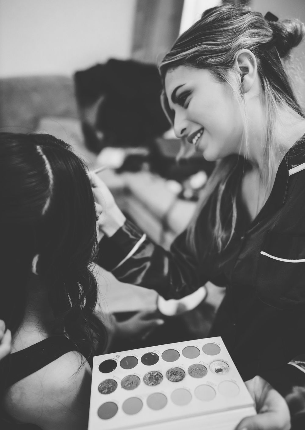 Makeup artists apply cosmetics during a wedding preparation.