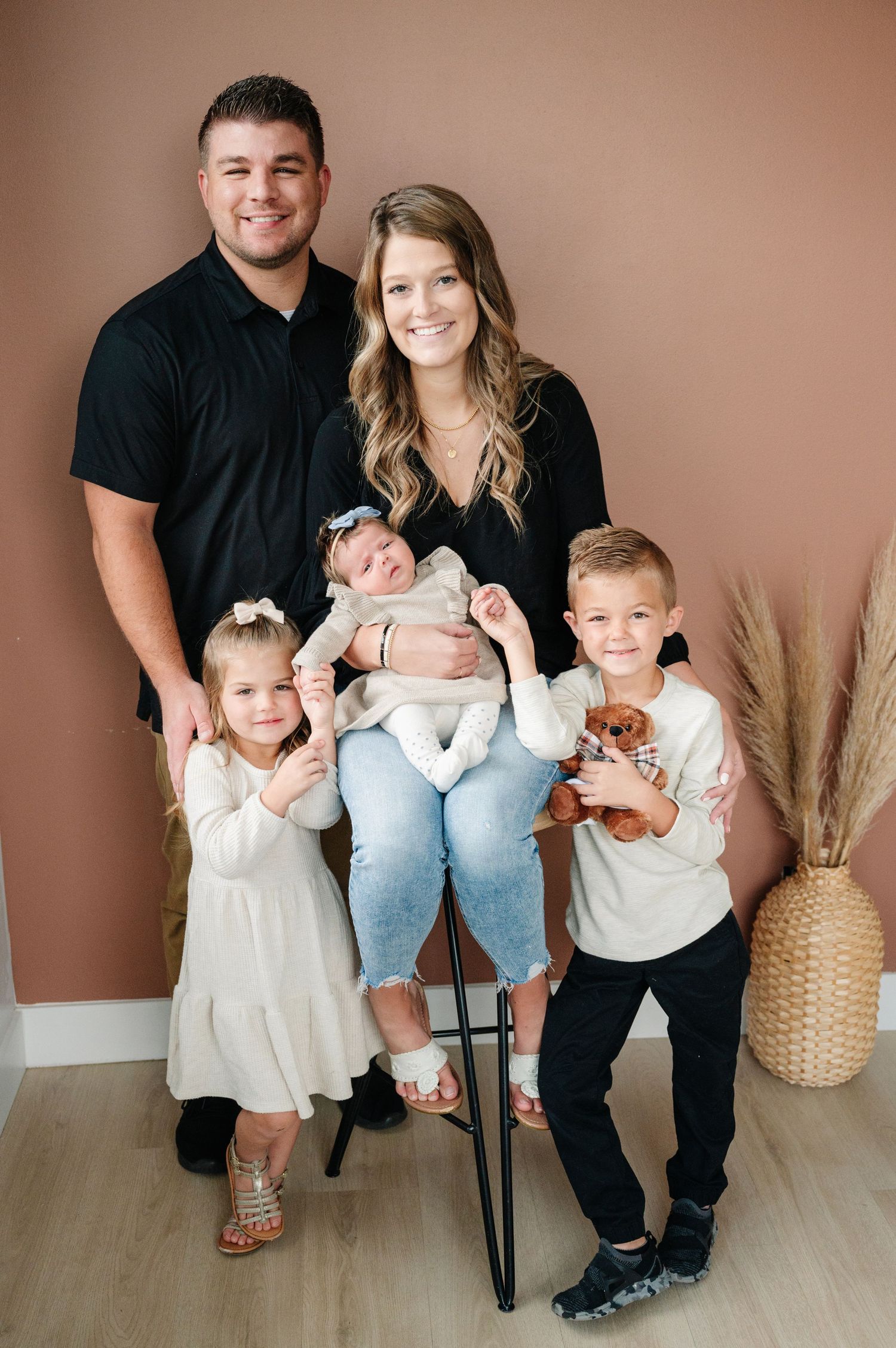 Family portrait against pink wall with decorative pampas grass.