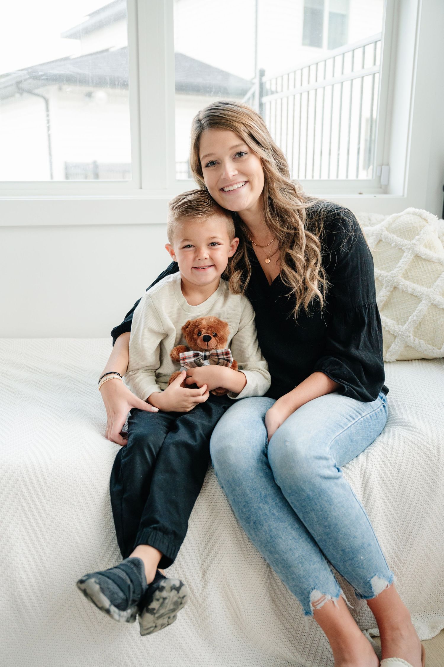 Cozy indoor portrait of parent and child sitting on white furniture.