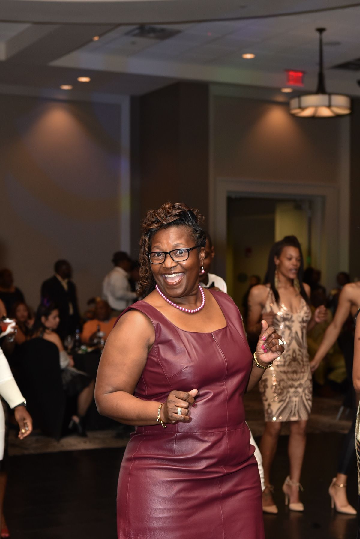 A guest in a burgundy dress enjoying a formal evening event with drinks and dancing.
