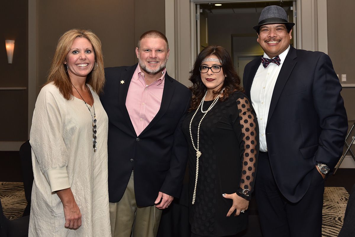 Group photo of attendees in formal business attire at an upscale indoor reception.