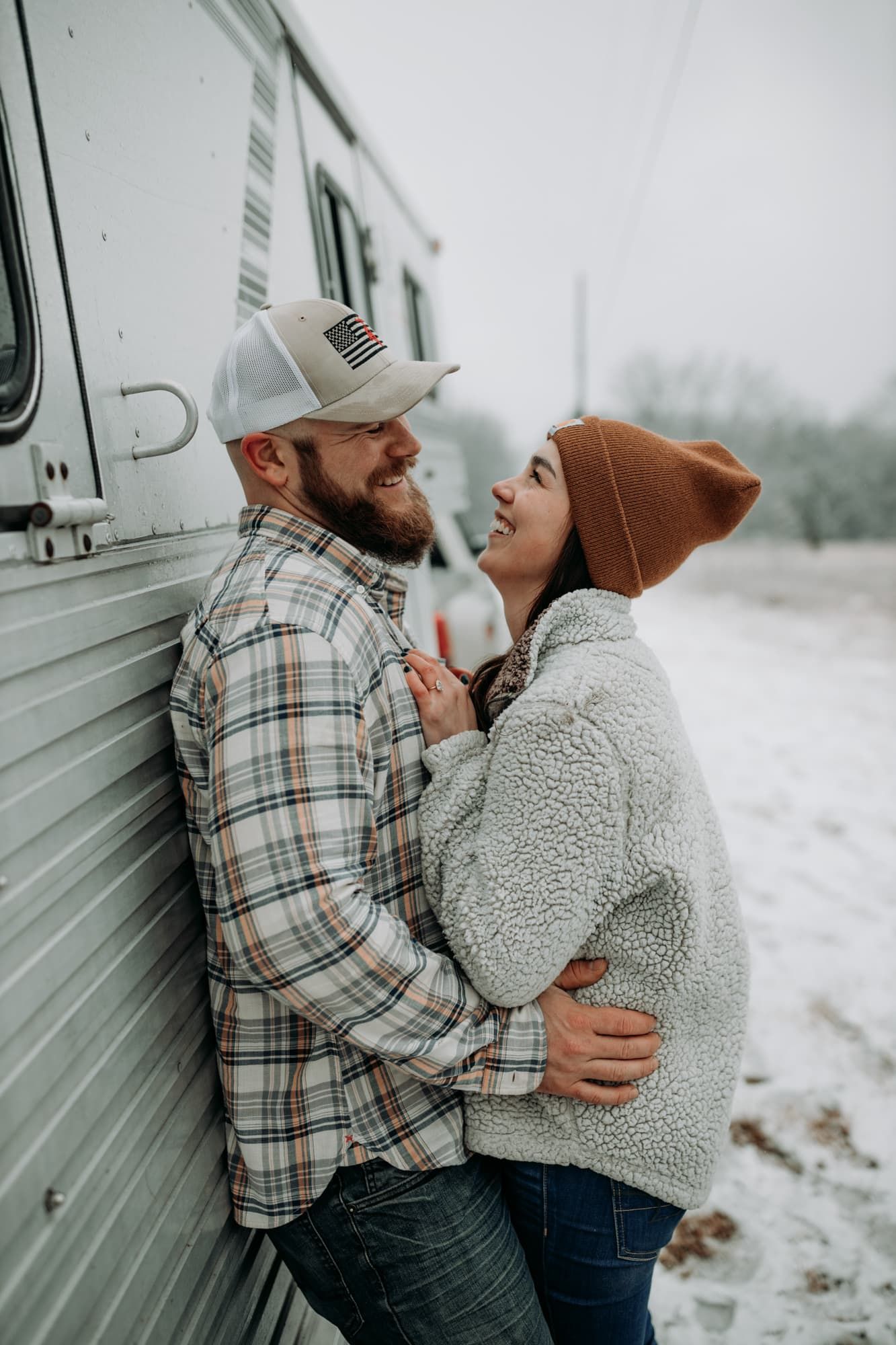 couple-against-horse-trailer-hugging-snow