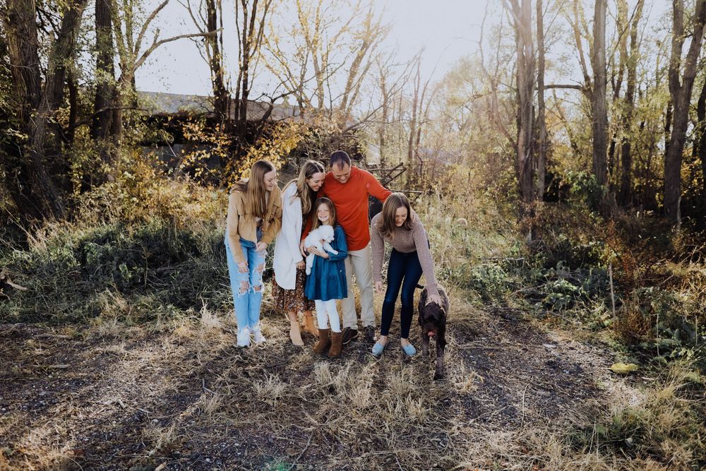 A group poses with their dogs on a wooded trail during an autumn photo session.