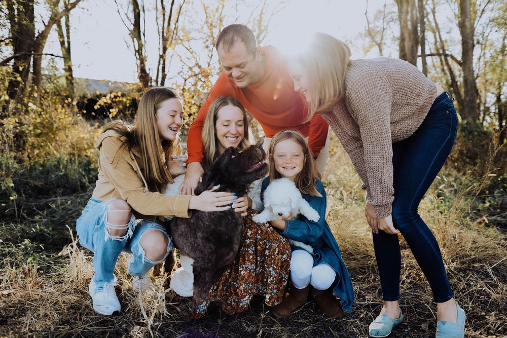 A group gathers closely together sharing laughter on a nature path during golden hour.