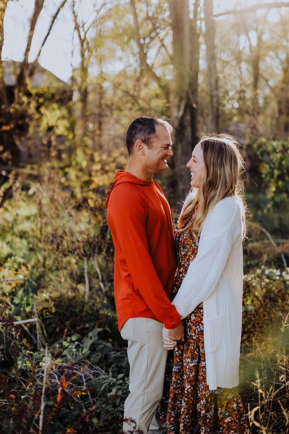 A couple shares an intimate moment while standing in autumn foliage.