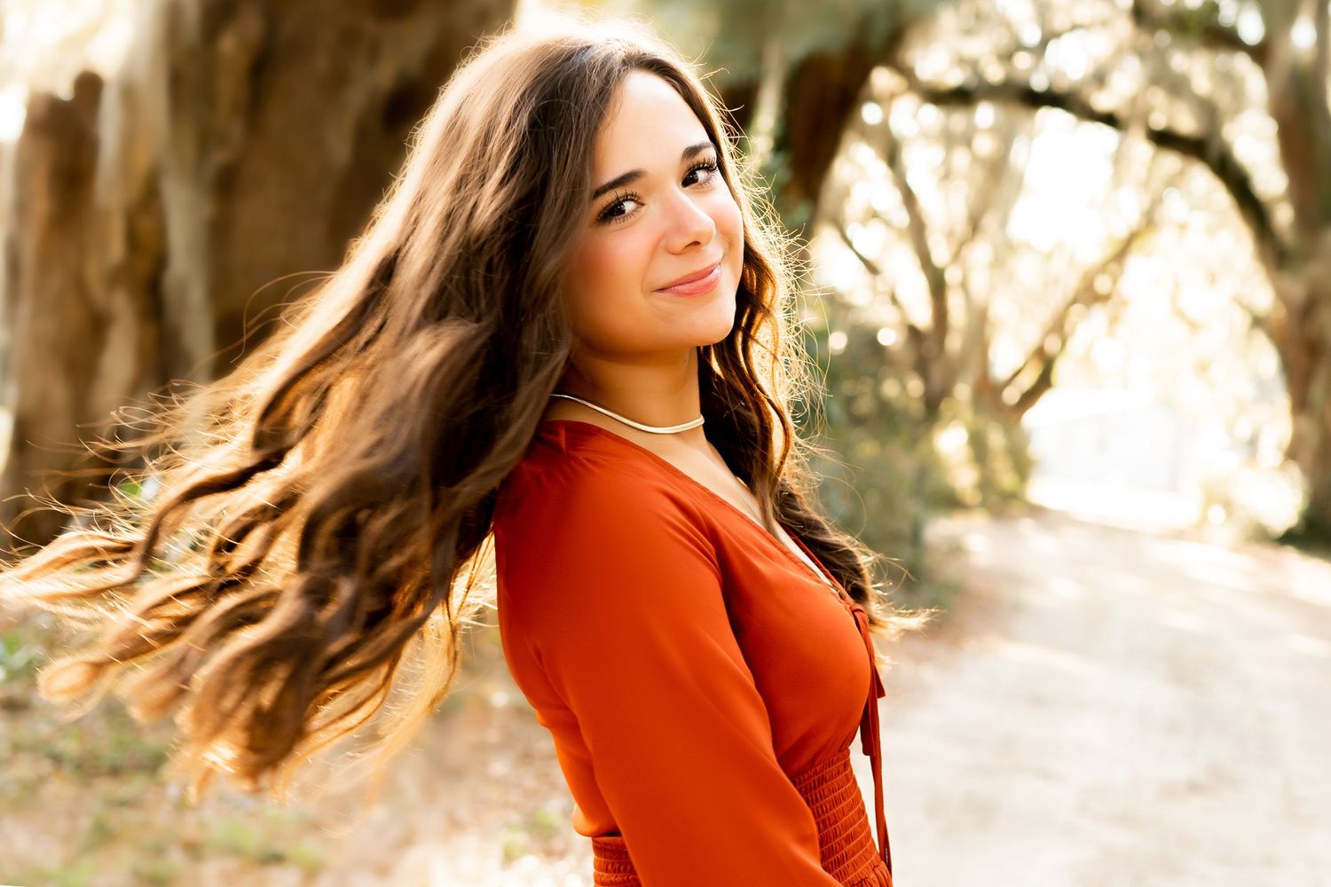 Autumn portrait session featuring a vibrant orange sweater in golden sunlight.